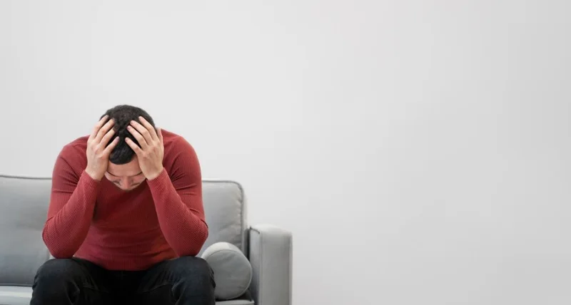 мужчина с кататонией держится за голову